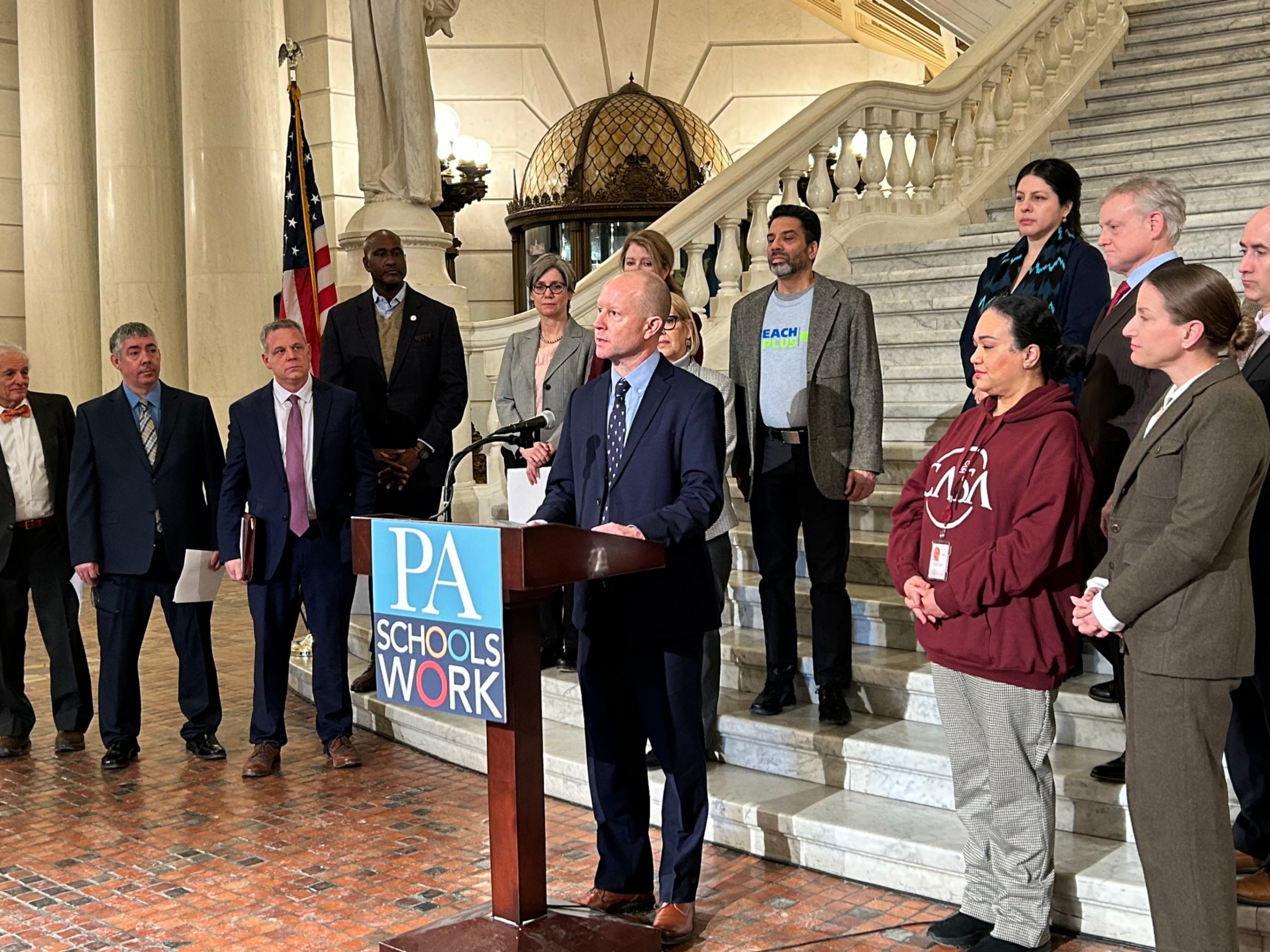 Superintendent Dr. Erich May speaks at a press conference in the state capitol building surrounded by other public school advocates.